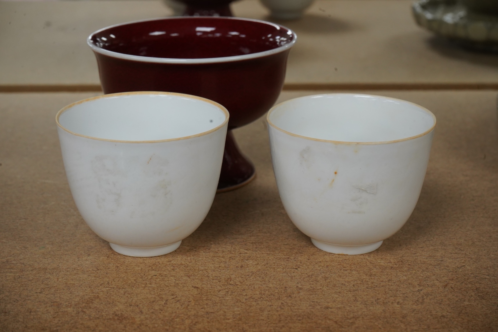 A Chinese red glazed stem cup together with two white glazed tea bowls, tallest 6.5cm